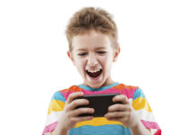 Smiling child boy playing games or surfing internet on smartphone