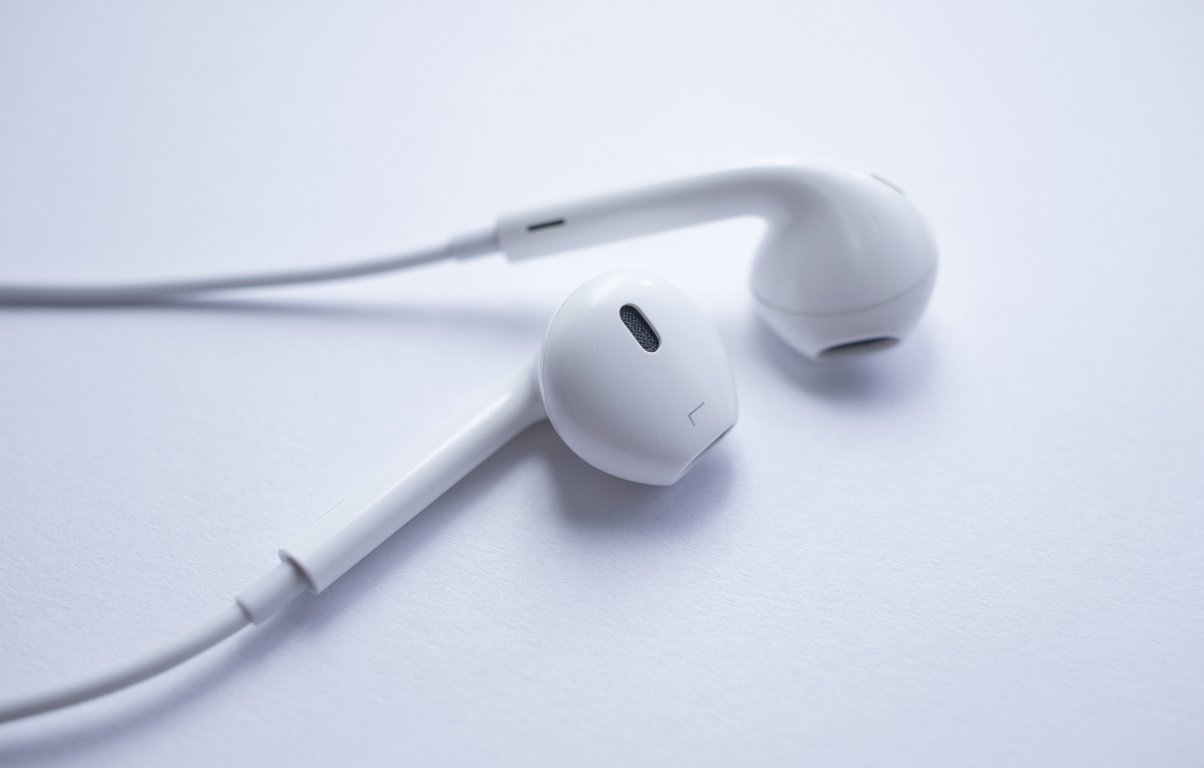Electronic modern earphones for playing music. Closeup shot of a pair of white earphones isolated on white. Focus is on left earphone.