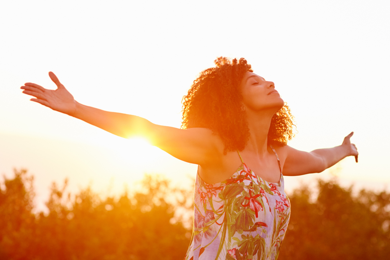 Woman outstretched arms in an expression of freedom with sunflar