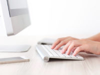 Female hands typing on a keyboard of computer iMac
