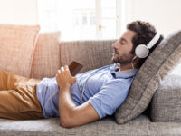 Man on his sofa listening to music with a smartphone