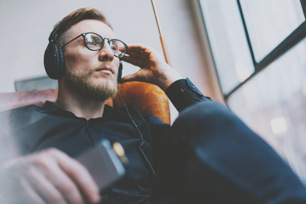 Portrait handsome bearded man glasses,headphones listening to music modern