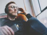 Portrait handsome bearded man glasses,headphones listening to music modern