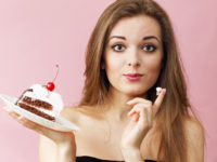 Woman eating the cream from a cream cake