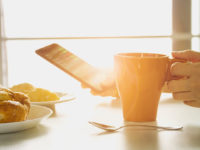 Fresh Breakfast with Hot Coffee, and Holding Smartphone in Morning Sunlight.