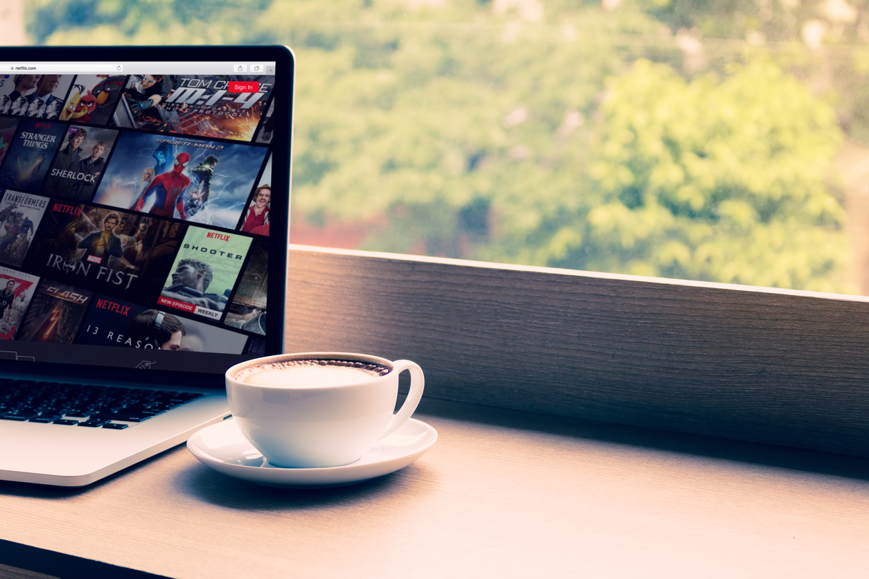 Netflix website showing on screen laptop with macbook pro at cafe. Netflix being popular internationally