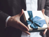 Man in suit offering gift with blue ribbon