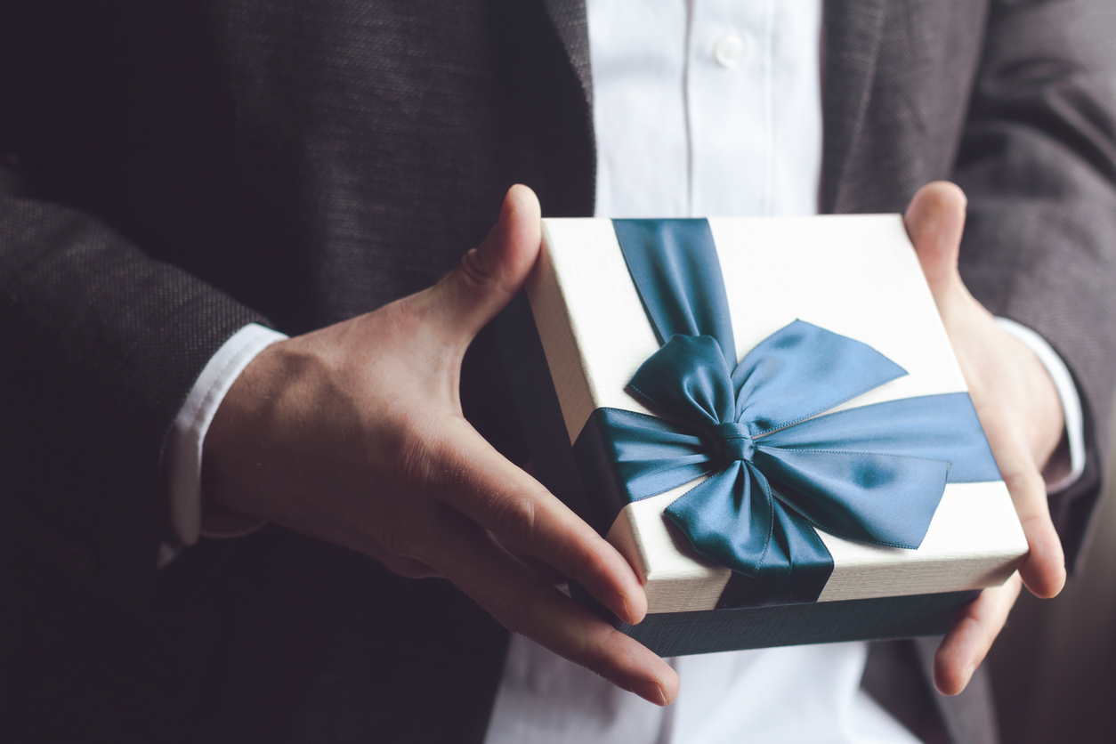 Man in suit offering gift with blue ribbon