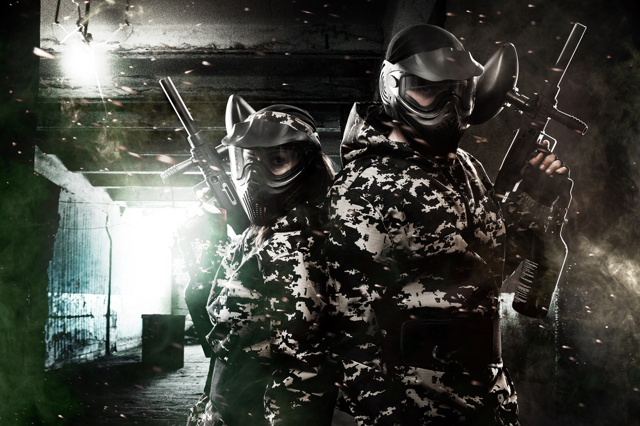 Two heavily armed masked paintball soldier on post apocalyptic background. Ad concept.