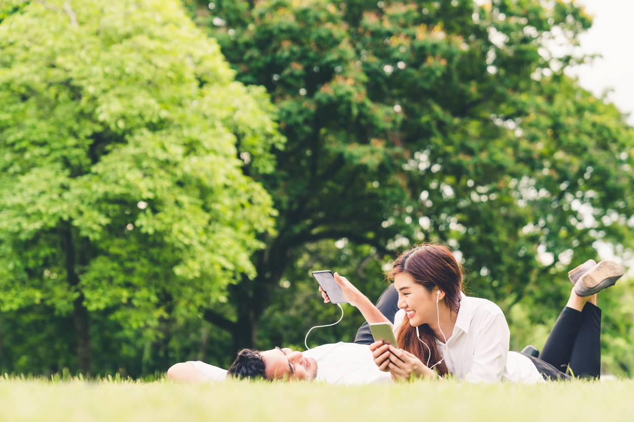 Young Asian lovely couple or college students listening to music together in the garden, with copy space. Leisure activity, Love relationship, wedding, or relaxing casual lifestyle concept