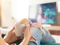 Young woman relaxing on the sofa at home, watching tv