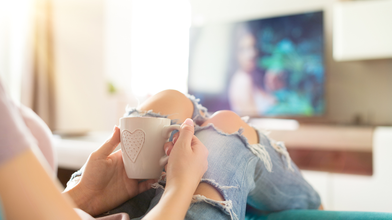 Young woman relaxing on the sofa at home, watching tv