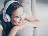 Chillout, satisfaction, therapy, wellness, leisure, lifestyle mode. Charmed adorable brown haired adorable model enjoying to the stereo sound in big modern ear phones in a room, nice break, good-day