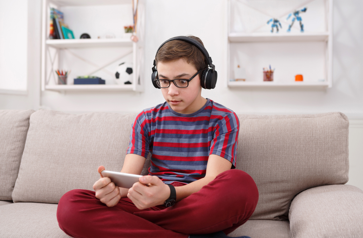 Excited teenage boy playing mobile game at home