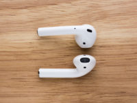 The airpods headset lies on a wooden table.