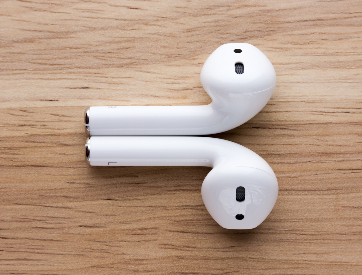 The airpods headset lies on a wooden table. Wireless headphones close-up.