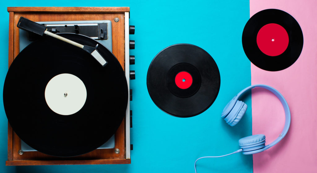 Retro vinyl player, lp records, headphones on blue pink background. Top view. Retro style. Flat lay.