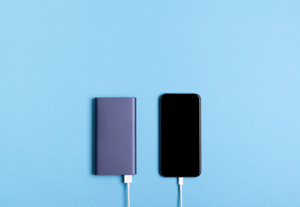 Smartphone charging with power bank on blue background