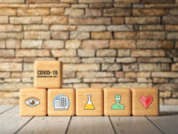 cubes with text COVID-19 and health icons in front of a brick wall - 3d rendered illustration