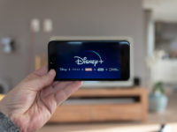 Disney+ startscreen on mobile phone. Disney+ online video, content streaming subscription service. Man holds his smartphone up and looks at disney plus