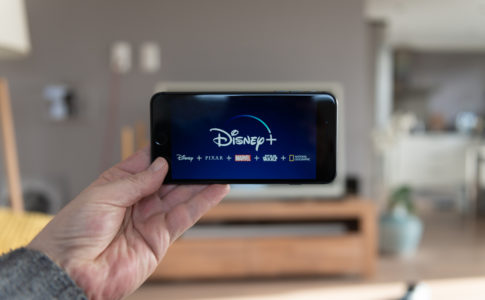 Disney+ startscreen on mobile phone. Disney+ online video, content streaming subscription service. Man holds his smartphone up and looks at disney plus