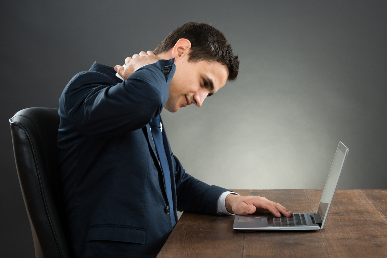 Businessman Suffering From Neck Pain Using Laptop At Desk