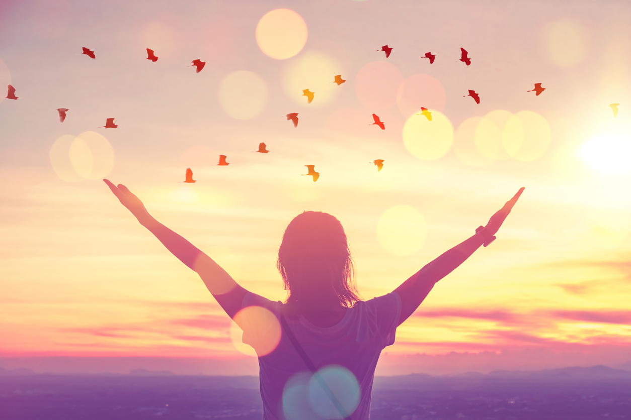 Freedom feel good and travel adventure concept. Copy space of silhouette woman rising hands on sunset sky at top of mountain and bird fly abstract background.