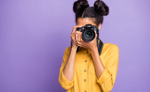 Photo of amazing dark skin lady holding photo digicam in hands photographing foreign sightseeing abroad wear yellow shirt trousers isolated purple color background
