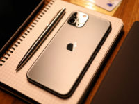 Apple iphone pro with silver pen on notebook