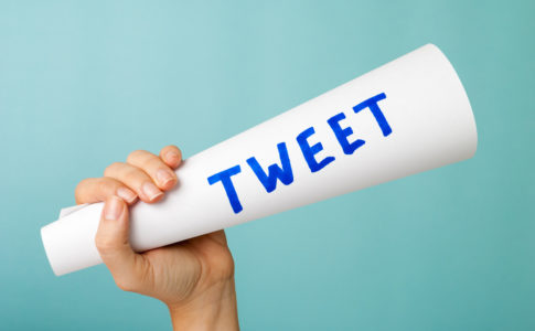 Hand showing blue tweet word handwritten, megaphone. Social media concept.