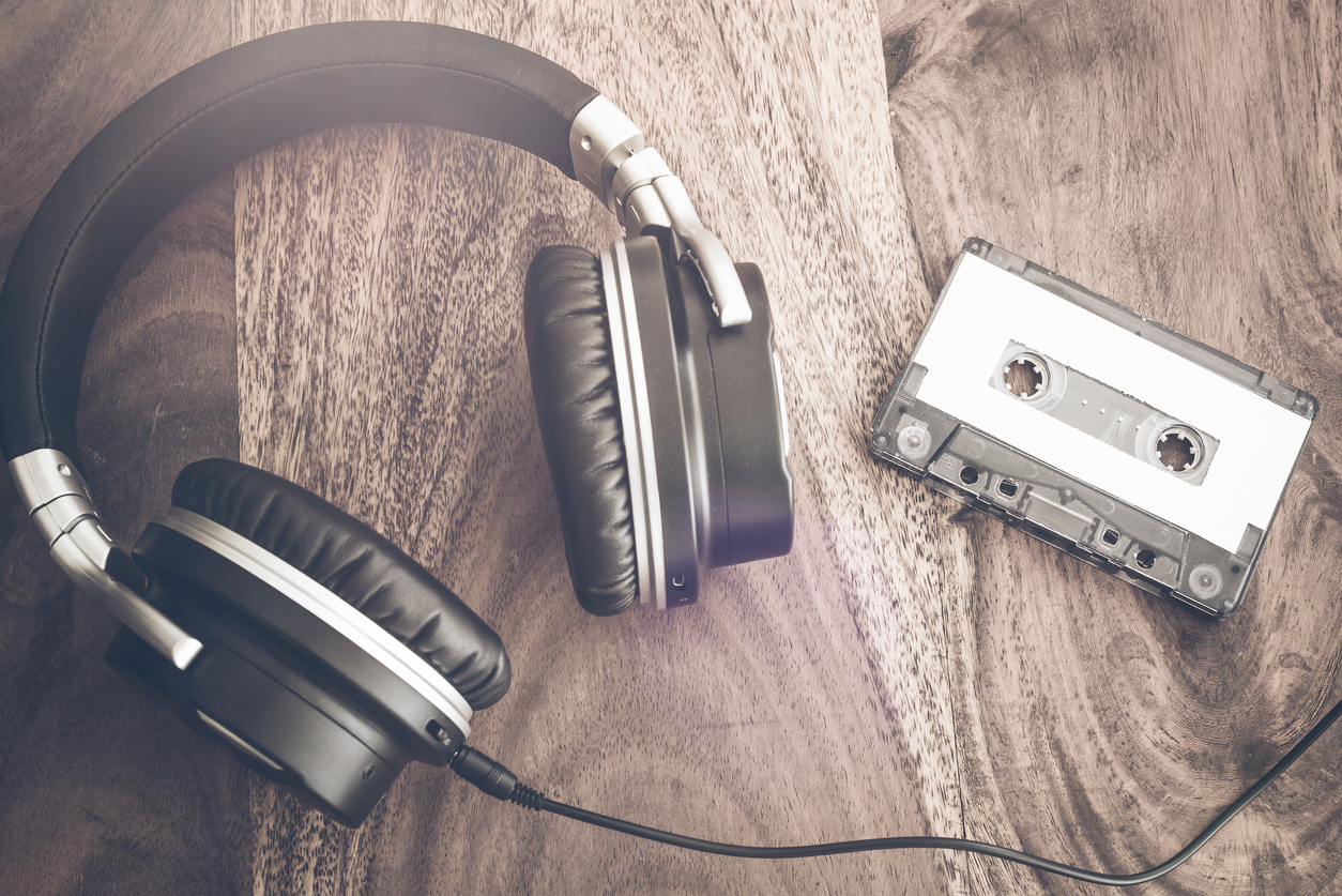 stereo headphones and audio cassette tape on rustic wooden table